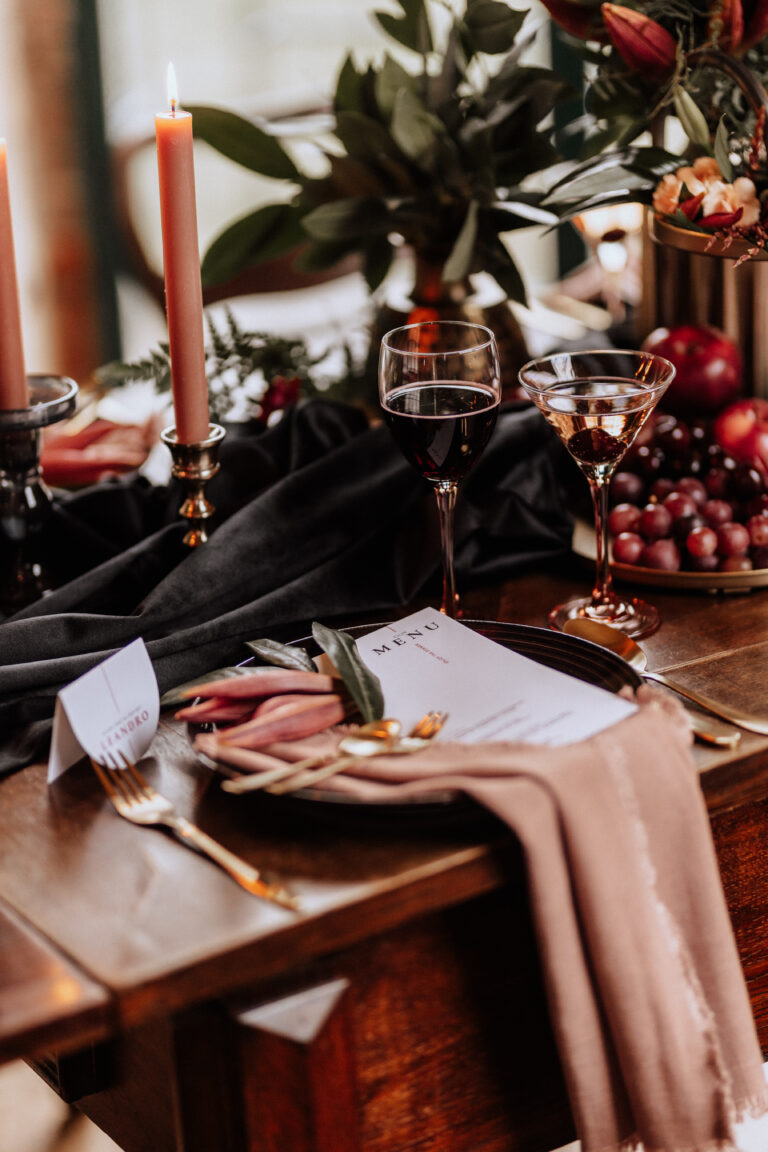 Eleganter gedeckter Tisch mit Kerzen, Weingläsern, Blumen und einer rosa Serviette auf einem Holztisch - die perfekte Inspiration für eine Hochzeitsdeko, empfohlen von Ihrem vertrauenswürdigen Hochzeitsplaner.