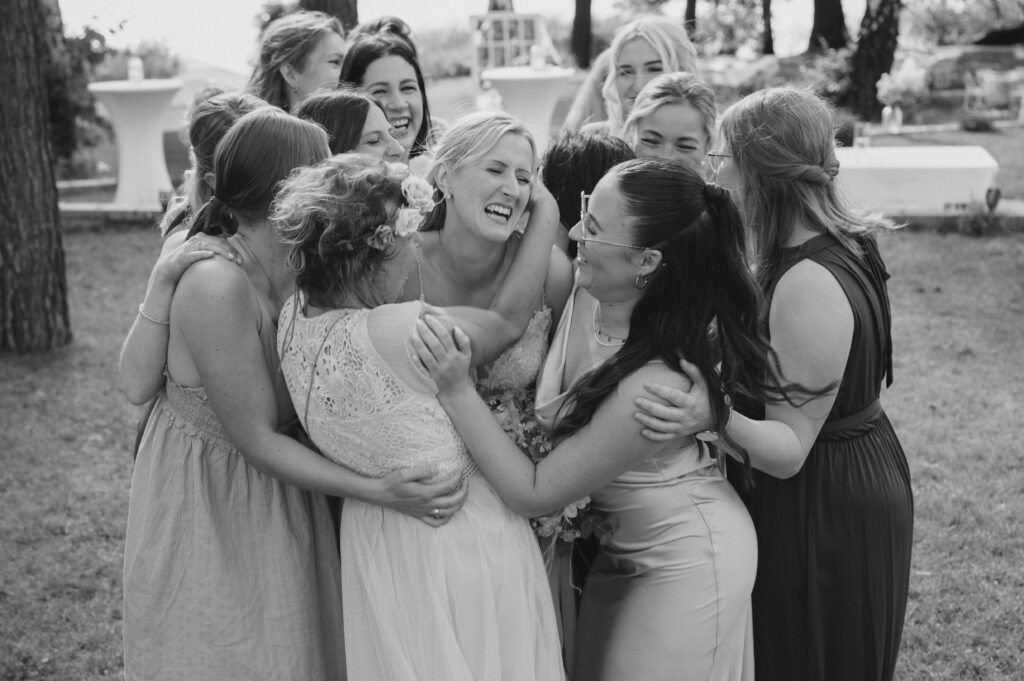 Eine Gruppe von Frauen, die sich freudig umarmen und lachen, auf einer Hochzeit in Brandenburg, umgeben von einer schönen Hochzeitsdeko.