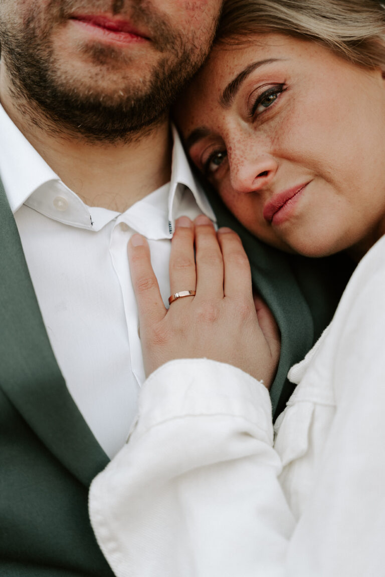 Eine Frau legt ihren Kopf auf die Brust eines Mannes und zeigt den Verlobungsring an ihrer Hand - ein Moment, der in Brandenburg eingefangen wurde und perfekt für eine Zeremonie der Freien Traurednerin ist.