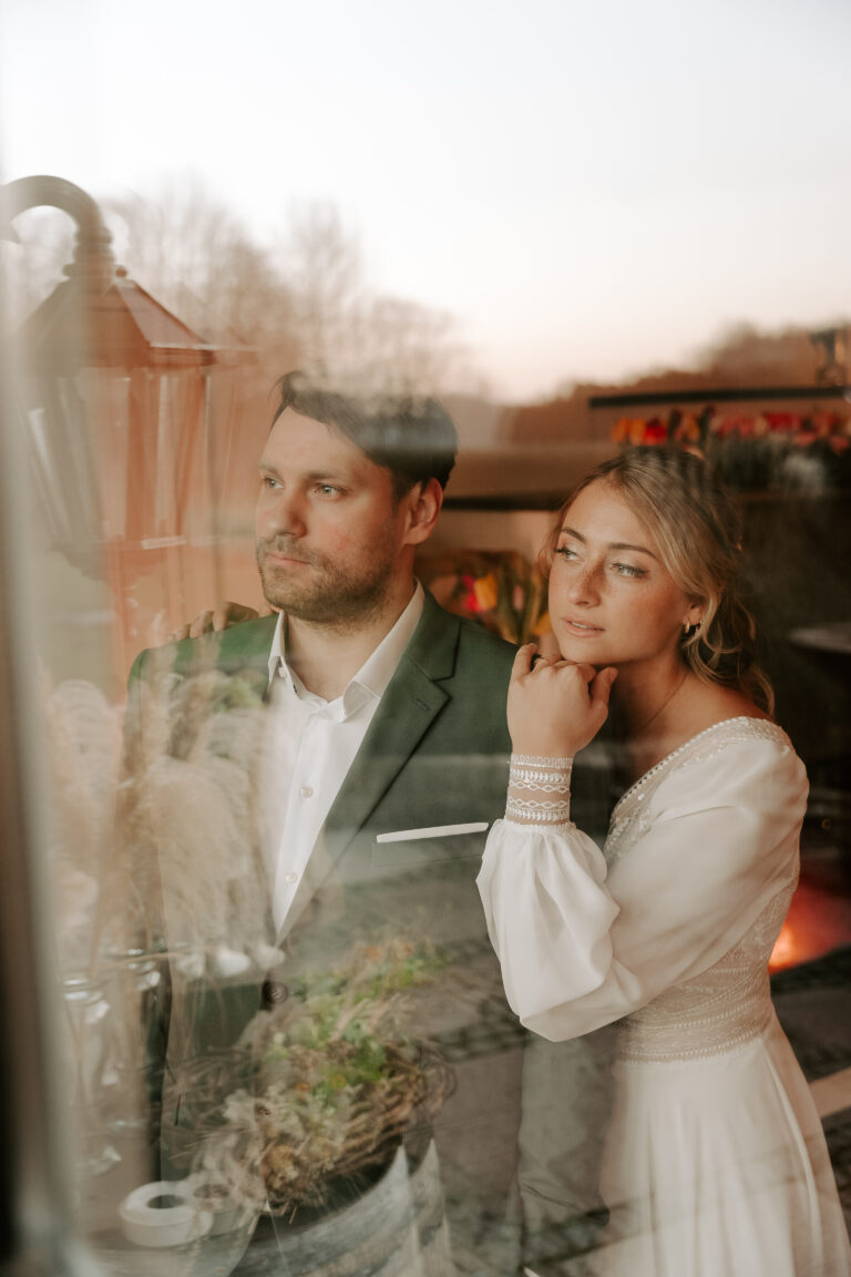 Ein formell gekleidetes Paar steht zusammen und blickt nachdenklich aus dem Fenster, vielleicht mit Hilfe eines Hochzeitsplaners, um sich ihre Traumhochzeit in Berlin vorzustellen.