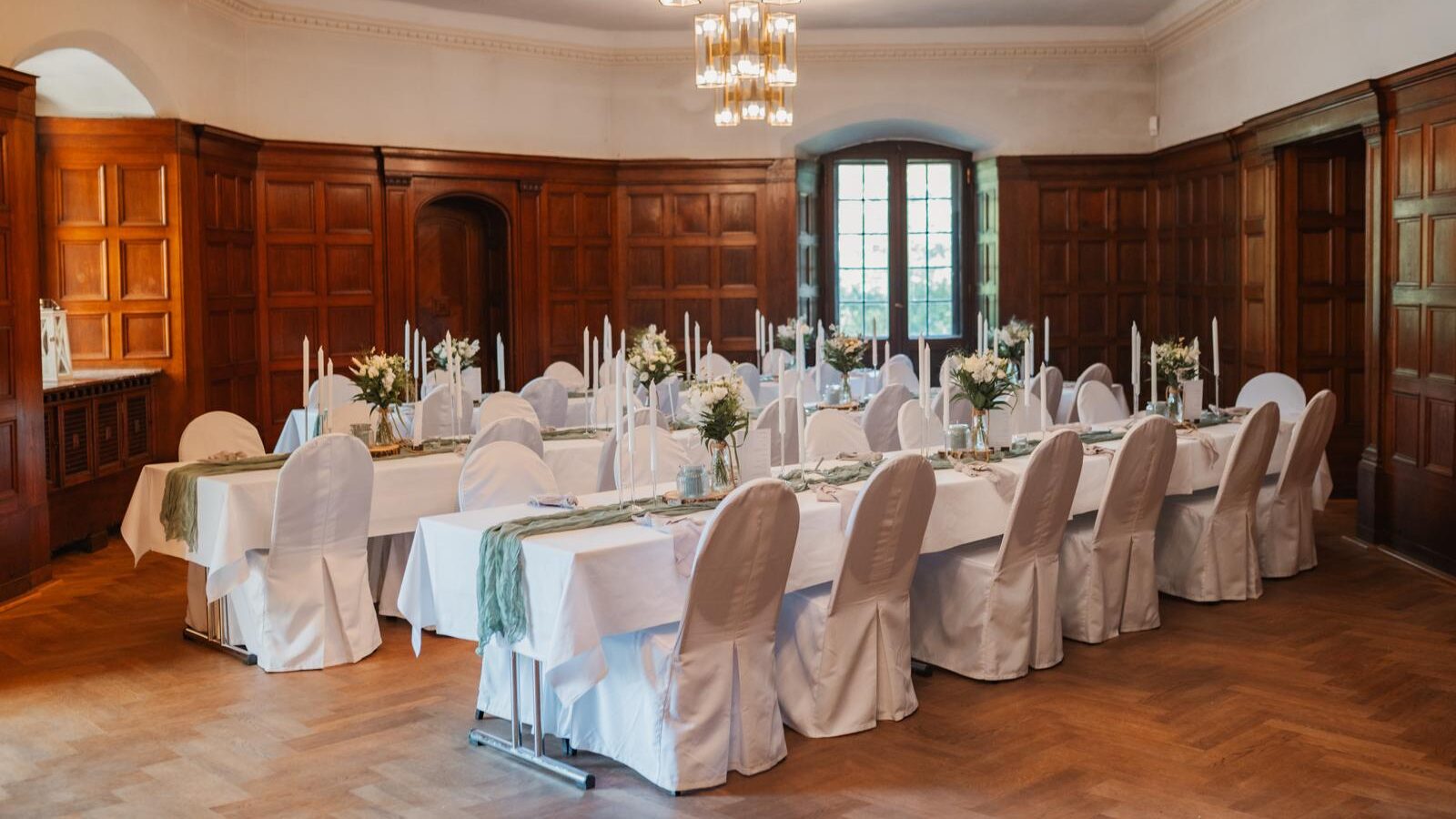 Elegantes Esszimmer mit Holzvertäfelung, weiß gedeckten Tischen und Stühlen für eine formelle Veranstaltung - perfekt für alle, die einen exklusiven Dekoverleih oder Dekorationsservice in Berlin suchen.