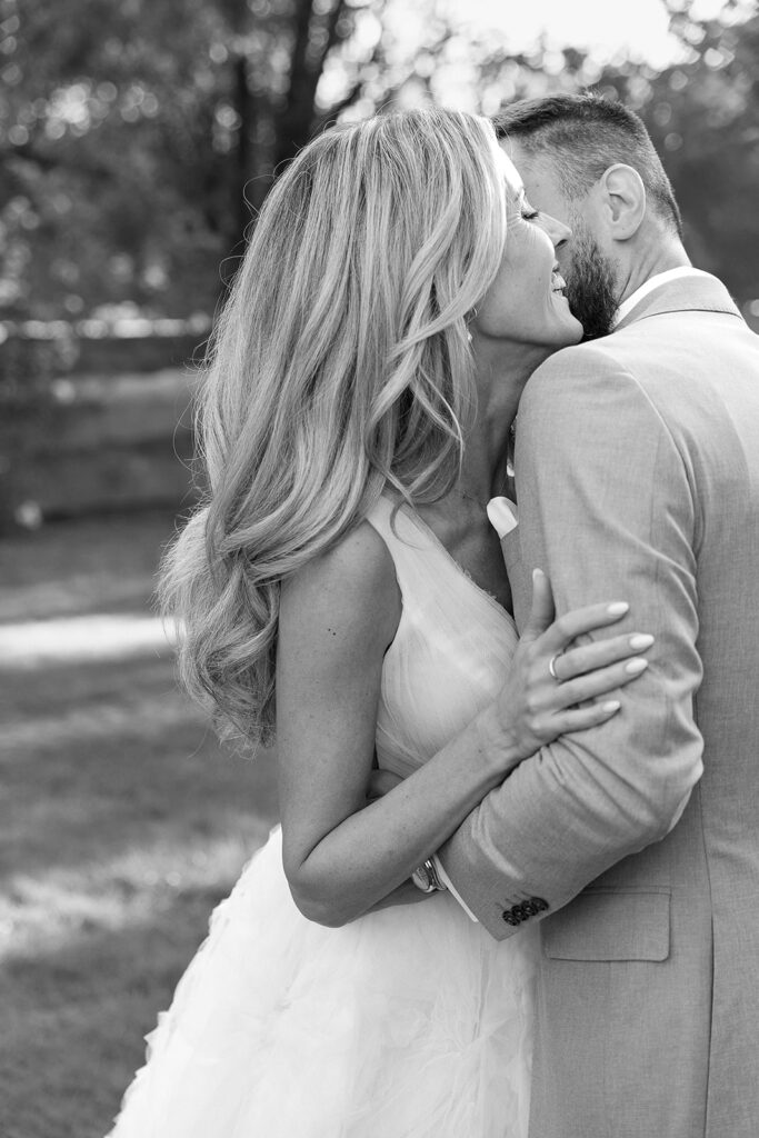 Eine Braut und ein Bräutigam umarmen sich während ihrer Freien Trauung im Freien und lächeln an ihrem Hochzeitstag fröhlich.